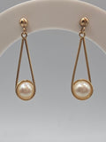 Solid 14K yellow gold pearl dangle earrings with elongated teardrop wire frames and ball post tops