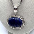 Sterling silver pendant necklace with a deep blue oval cabochon in an ornate beaded and rope twist frame on an 18 inch chain